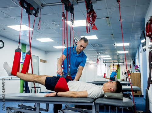 Physiotherapy. Suspension training therapy. Young man doing fitness traction therapy with suspension-based exercise training system.