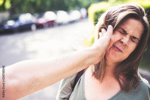 Mother hitting daughter on the street in daylight – Parent abuse outdoor in public – Hand slapping a teen’s face – Concept of awareness raised against aggressive bully parents