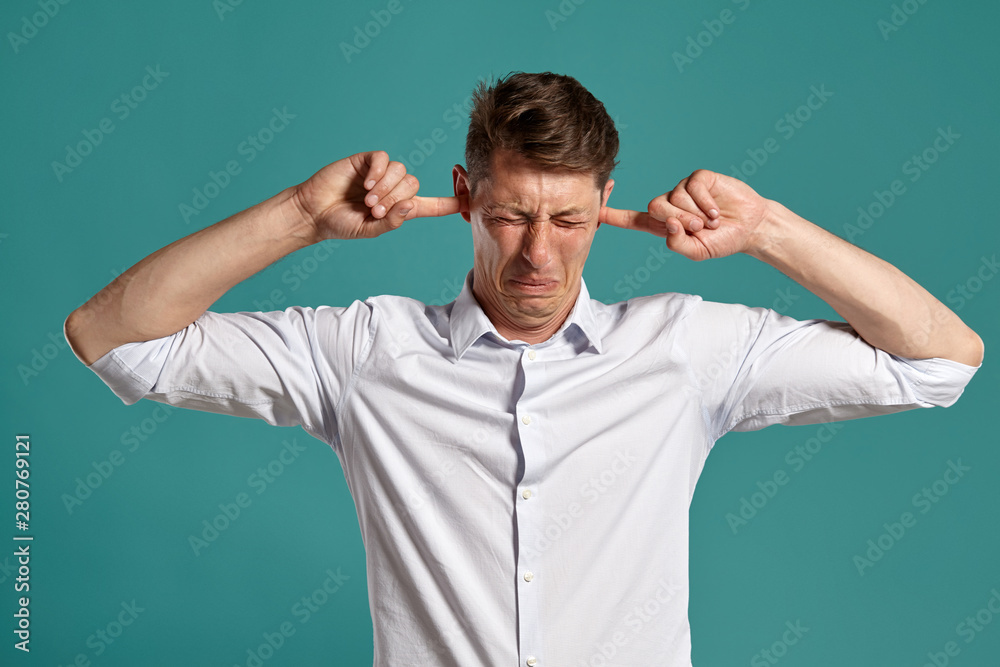 Portrait of a young brunet man posing in a studio against a blue background. Portrait of a young brunet man posing in a studio against a blue background.