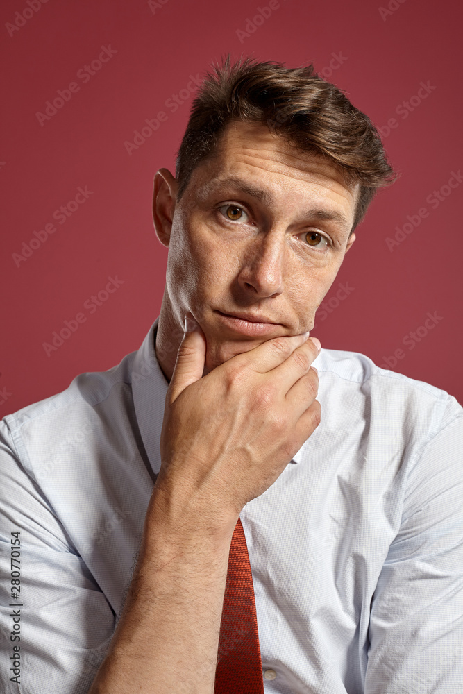 Portrait of a young brunet man posing in a studio against a red background. Portrait of a young brunet man posing in a studio against a red background.