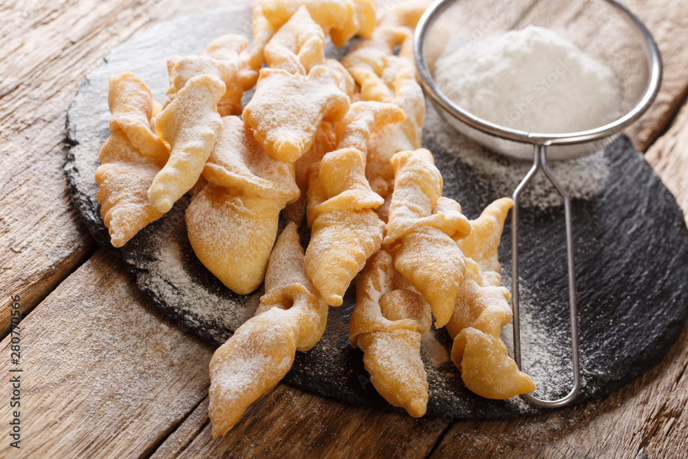 Fototapeta premium Freshly made Angel Wings Cookies with powdered sugar close-up on the table. horizontal