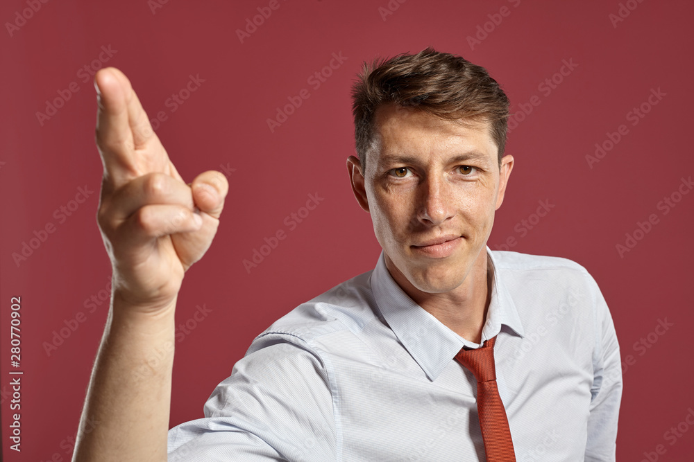 Portrait of a young brunet man posing in a studio against a red background. Portrait of a young brunet man posing in a studio against a red background.