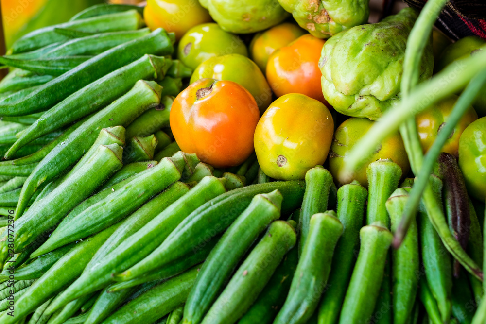 Closeup of vegetable okra (AKA ladies' fingers or ochro), ripe tomatoes and chayote or sayote. Selective focus. Closeup of vegetable okra (AKA ladies' fingers or ochro), ripe tomatoes and chayote or sayote. Selective focus.