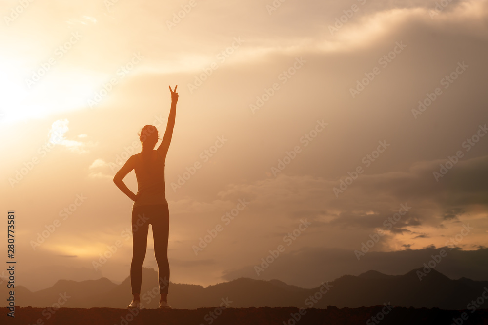 silhouette strong woman standing and fighting  movitation feeling on top of mountain