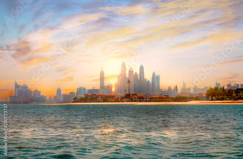 Dubai at sunset. Skyscrapers and Persian gulf with beautiful sun reflection. UAE, United Arab Emirates. 