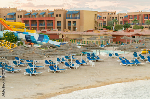 Umbrellas and chaise lounges on the beach. Scenic view of private sandy beach with sun beds from the sea