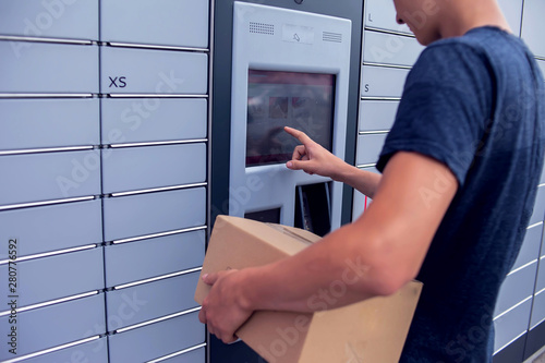 Fototapeta Client using automated self service post terminal machine or locker to deposit a