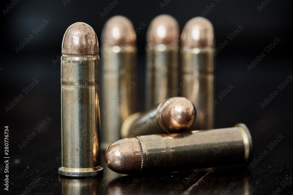 Brass handgun ammunition against a wooden backdrop Brass handgun ammunition against a wooden backdrop
