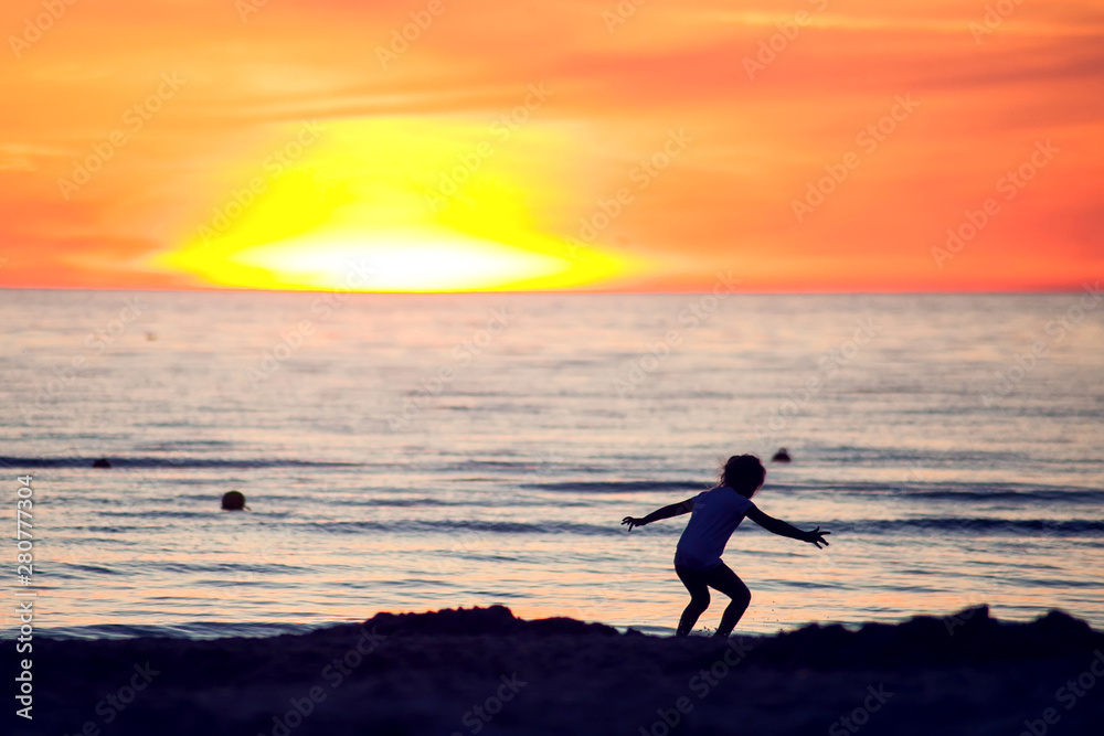 A silhouette of a child on the beach on sunset. Children, summer and holiday concept A silhouette of a child on the beach on sunset. Children, summer and holiday concept
