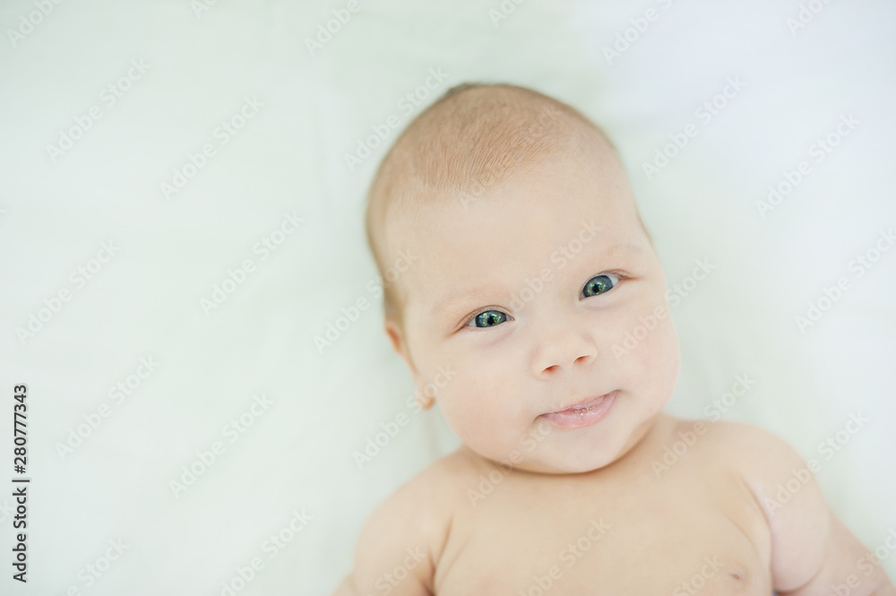 Close-up of three months old baby girl with blue eyes. Newborn child, little adorable smiling girl looking at camera.