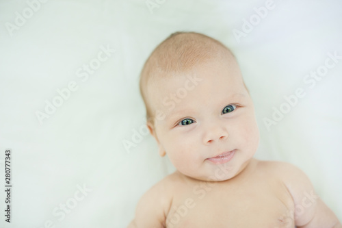 Close-up of three months old baby girl with blue eyes. Newborn child, little adorable smiling girl looking at camera.