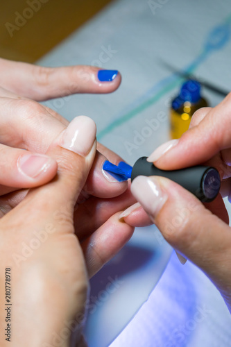 Beautiful manicure process. Nail polish being applied to hand  polish is a blue color. closeup. vertical photo