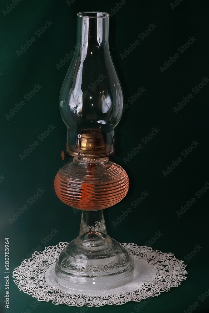 Antique Oil Lamp on Lace Doily against Dark Green BG