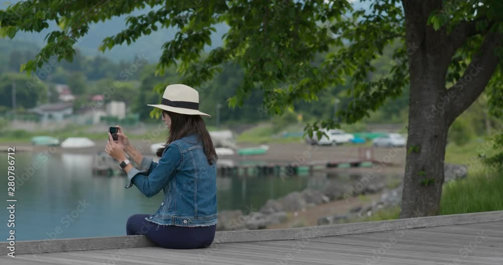 Woman take photo and sit on lake side Woman take photo and sit on lake side