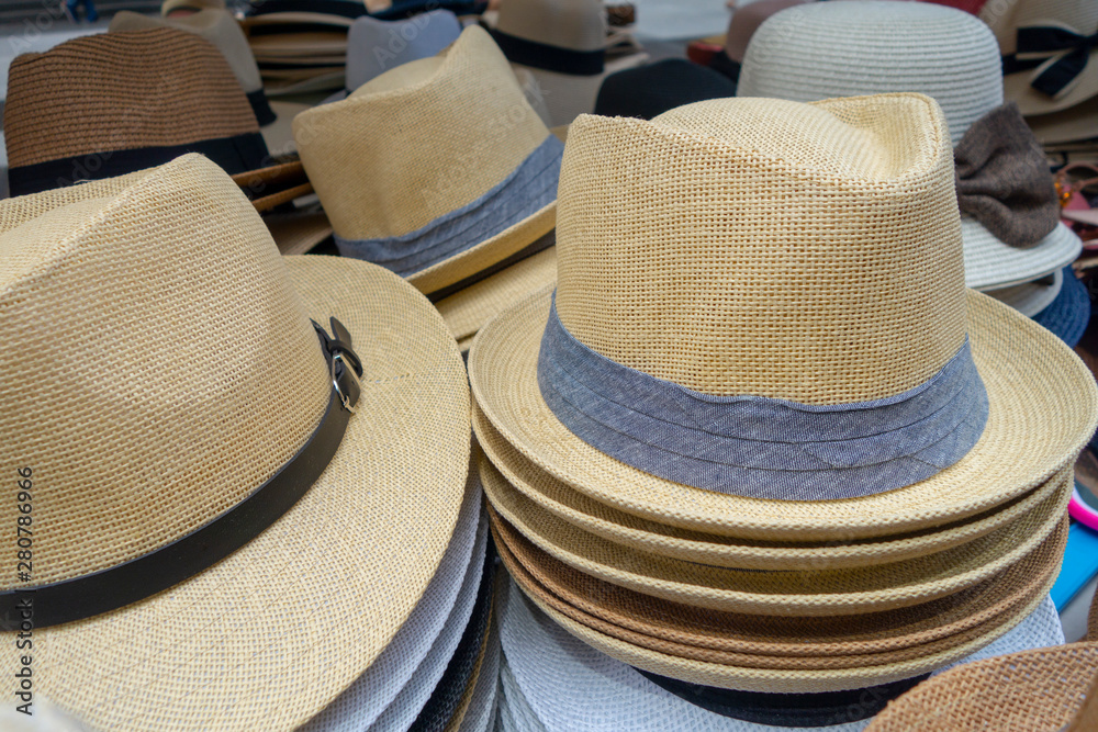 Woven tan grey and white hats on display at the market