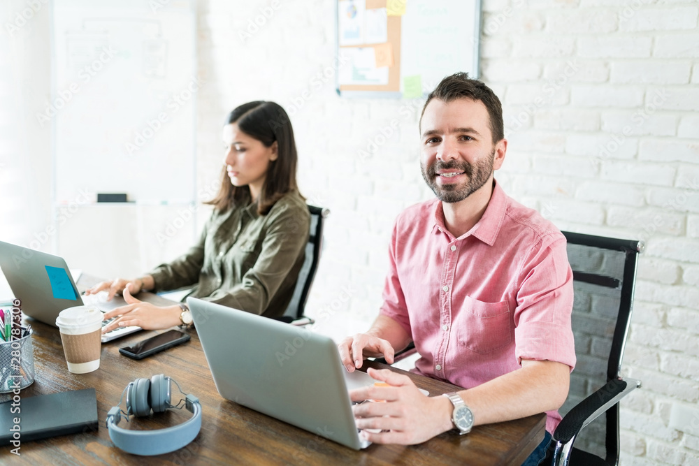 Male And Female Colleagues Using Computer At Desk