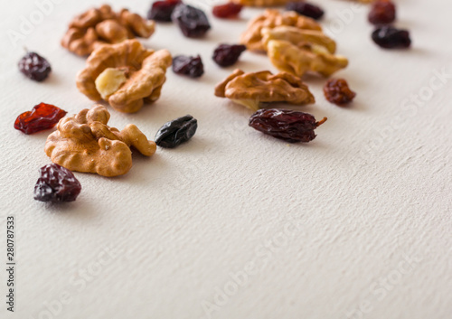 A variety of peeled walnuts and raisins on a white wooden background. View from above. Plenty of space for text.