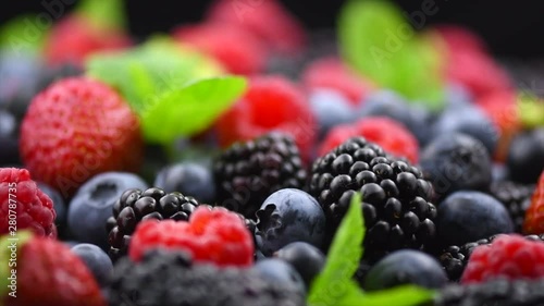 Berries. Various colorful berries background. Strawberry, raspberry, blackberry, blueberry closeup over black. Healthy eating. Rotation. Slow motion 4K UHD video footage. 3840X2160 photo