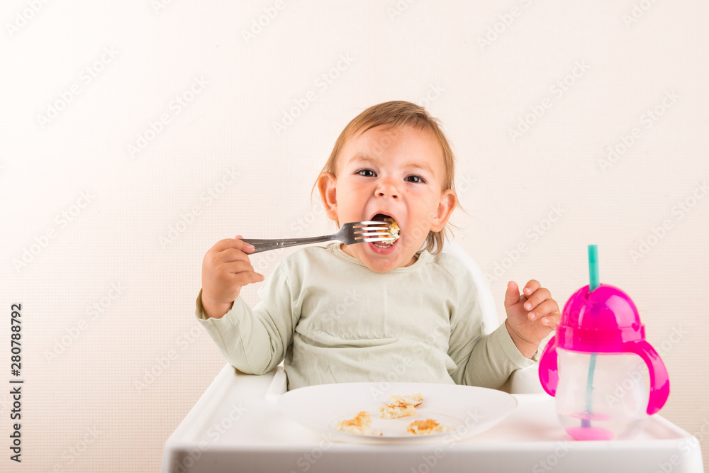 Baby toddler eating pancakes with fork. Isolated. Copy space