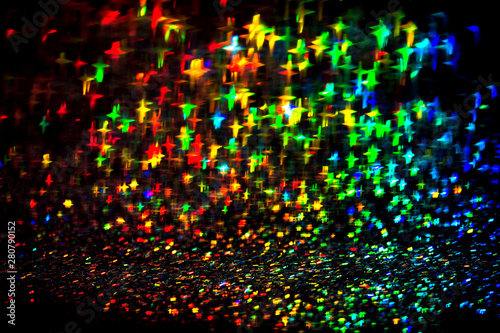 Multicolor neon lights star flares and rainbow glitter on isolated black background. Bokeh lens flare glow. Festive backdrop