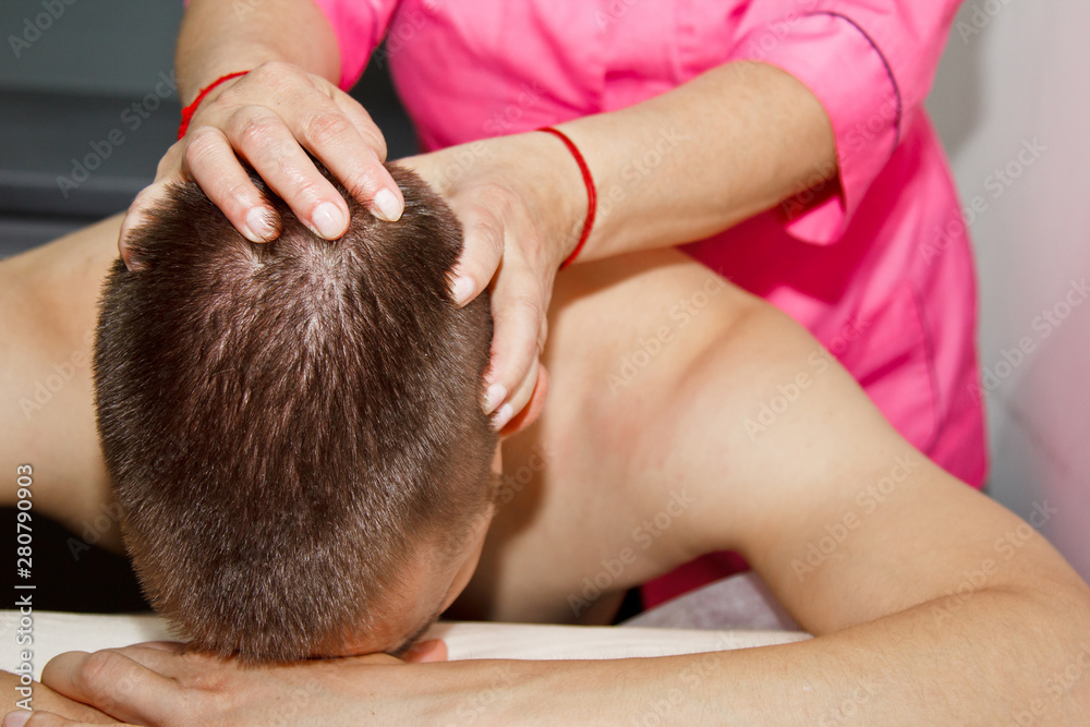professional therapeutic neck and head massage. man the athlete in a massage room. pain recovery procedure. Female physiotherapist doing manipulative spine treatment on young patient professional therapeutic neck and head massage. man the athlete in a massage room. pain recovery procedure. Female physiotherapist doing manipulative spine treatment on young patient