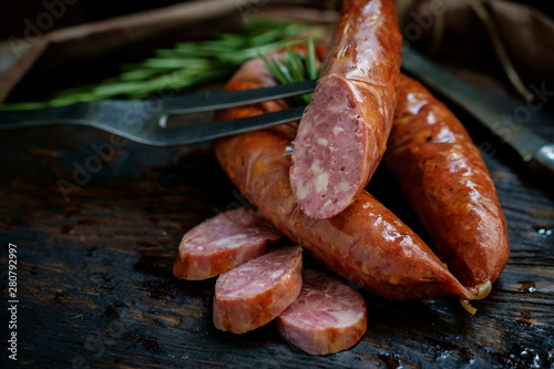 Obraz na plátně Bavarian smoked sausages from pork cut on a wooden Board