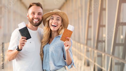 Happy couple smiling with flight tickets and passports at airport photo