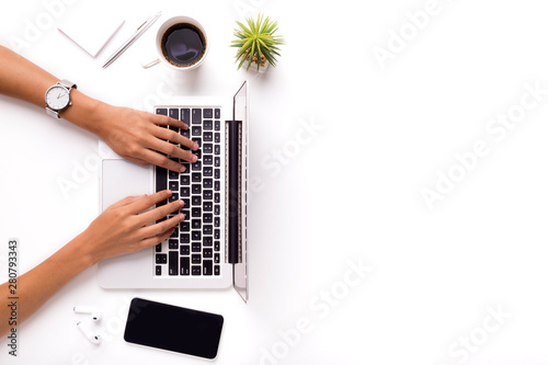 Woman typing on laptop on clean white office table with plant photo