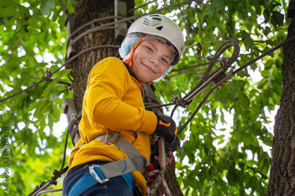  Active brave little boy enjoying climbing at treetop adventure park