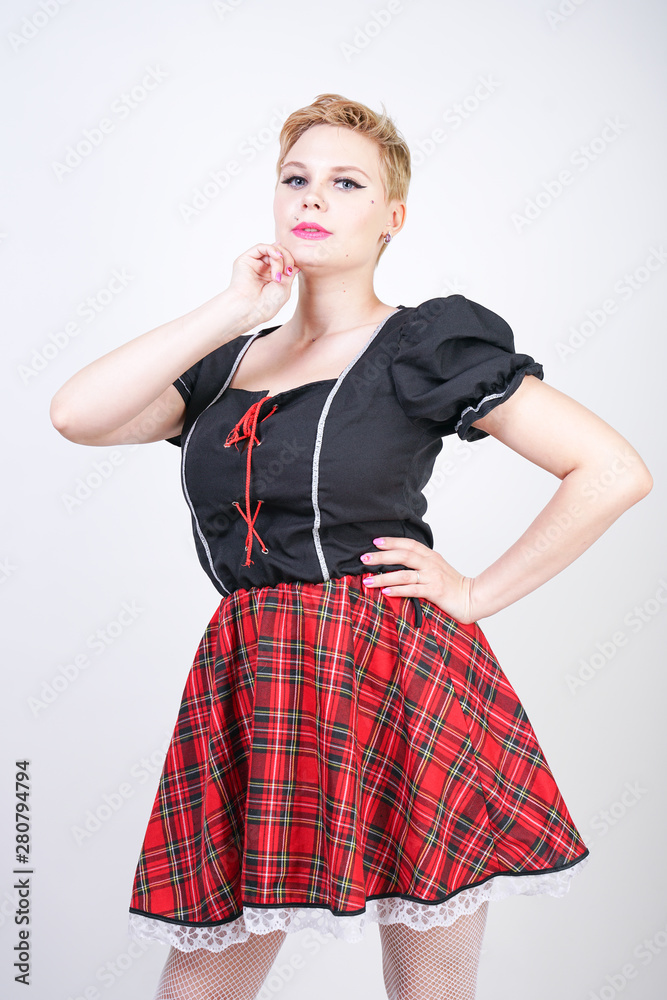 cute short hair blonde plus size female in holiday fun black red playful dress on white studio background alone