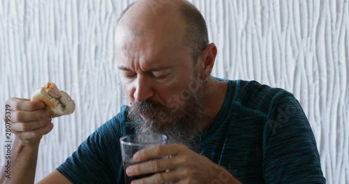 50 years old man having a breakfast, eating hot dog and drinking cola drink, real people