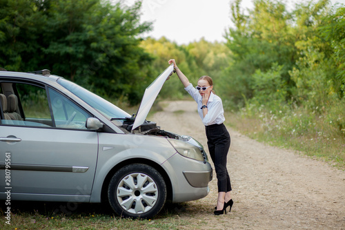 Young woman by the roadside after her car has broken down She opened the hood to see the damage © volody10