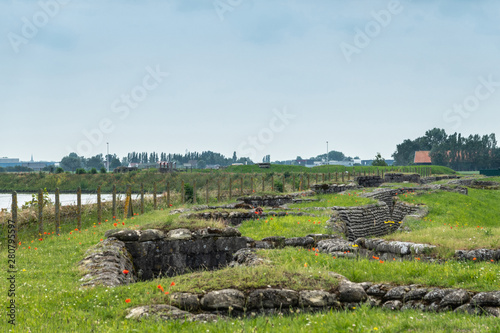 Fényképezés Diksmuide, Flanders, Belgium -  June 19, 2019: Overview of Historic WW1 Trenches, called Dodengang along IJzer River, shows gray-brown stone-hard sandbags, green grass, red poppies