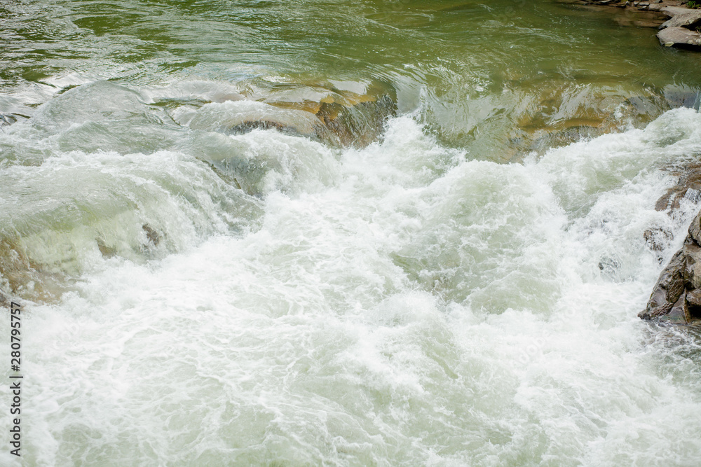 Stones and mountain river with small waterfall, blurred background, the flow of a mountain river Stones and mountain river with small waterfall, blurred background, the flow of a mountain river