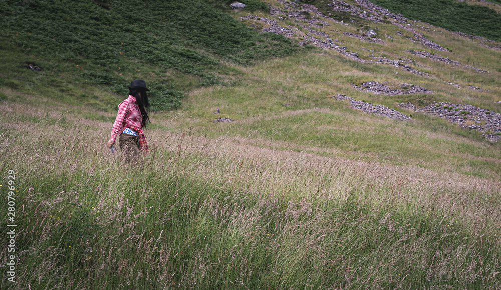 Woman walking on the hill in the Highlands of Scotland Woman walking on the hill in the Highlands of Scotland