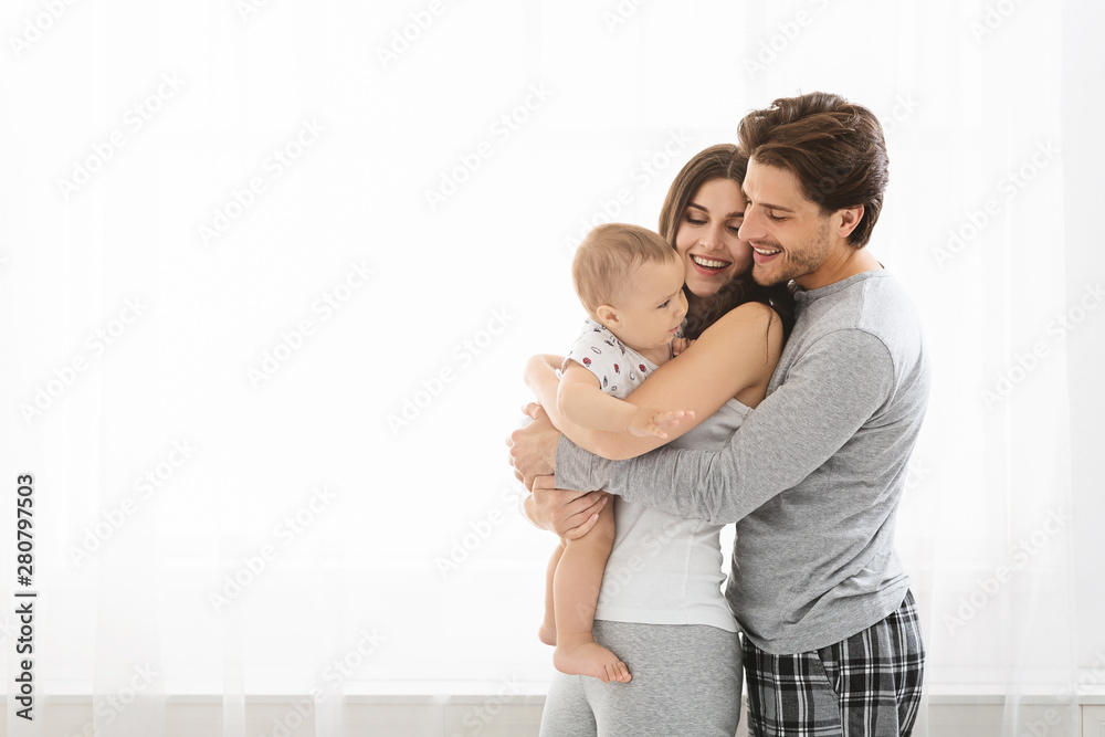 Loving parents cuddling with little baby son at window - obrazy, fototapety, plakaty 