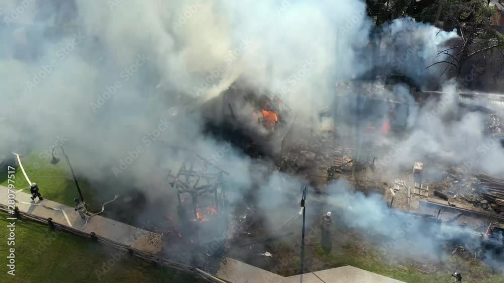 Fire fighters have their work cut out for them as they try to contain huge fire during high winds causing black smoke. 4K footage from drone