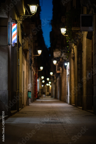 Blurred downtown alley at night with barbershop or hairdresser's sign on the wall