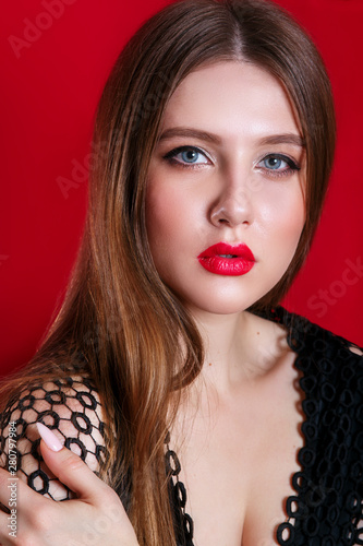Close-up studio portrait of beautiful woman with bright make-up and red lips