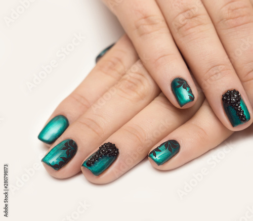 Nails with green cat-eye nail polish and black chevron design