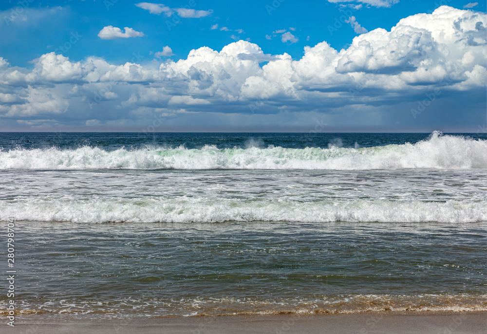 Fototapeta premium Sandy beach empty. Blue cloudy sky, blue sea with waves