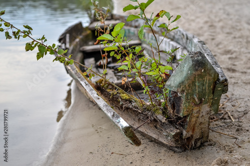 Close uu of old ruined fishing boat left on the lake shore  photo