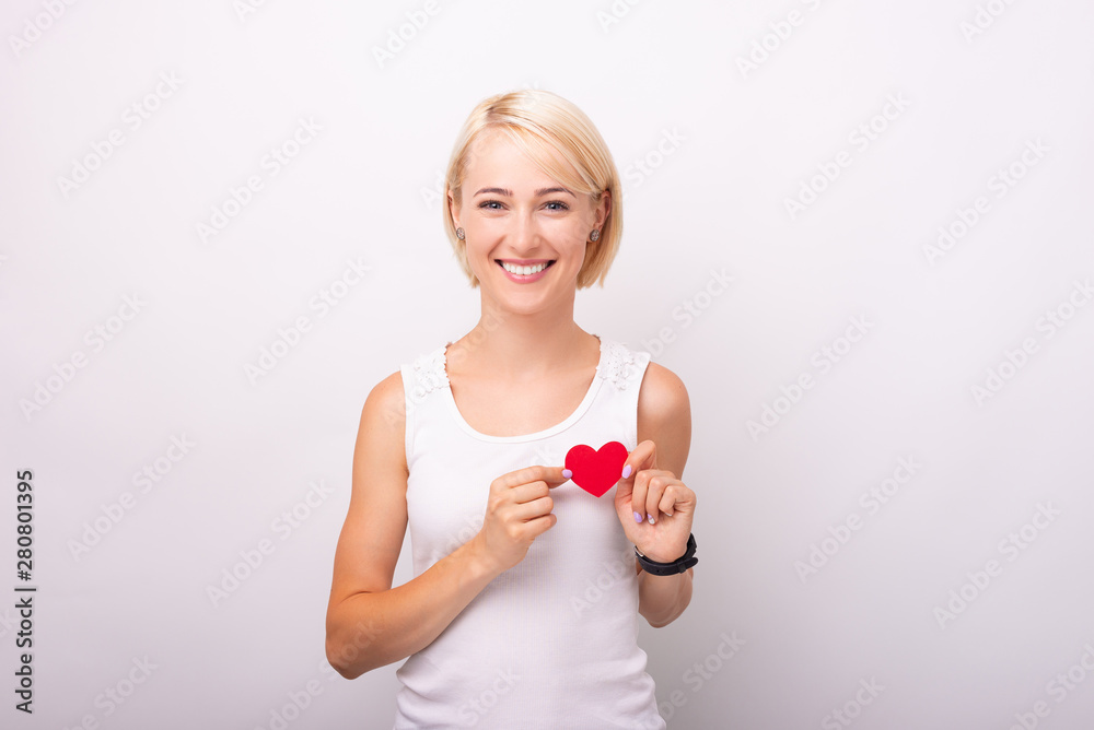 Portrait of smiling young woman holding red heart shape over chest Portrait of smiling young woman holding red heart shape over chest