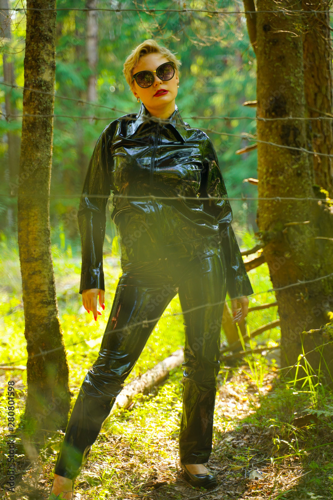 dangerous woman in a rubber suit in the woods behind barbed wire