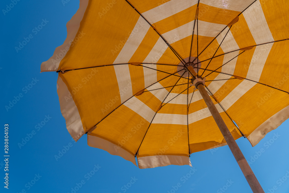 a bright yellow parasol stretched out on the beach