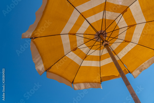 Obraz na płótnie a bright yellow parasol stretched out on the beach w salonie