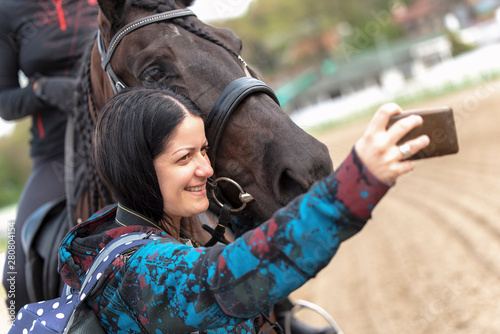 Fototapeta Naklejka Na Ścianę i Meble -  Young woman taking a self portrait, selfie, with her favourite animal - a black braided mare