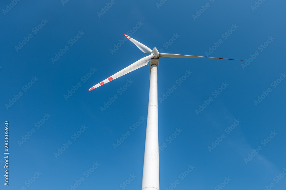 rotating blades of a windmill propeller on blue sky background. Wind power generation. Pure green energy. rotating blades of a windmill propeller on blue sky background. Wind power generation. Pure green energy.