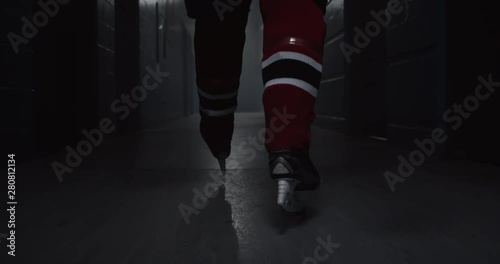 A hockey player walks down a hallway with intensity towards hockey arena featuring his hockey skates, building drama, 4K