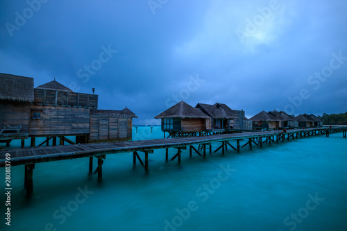 Water villa and wooden path of Luxury Maldives resort at sunrise